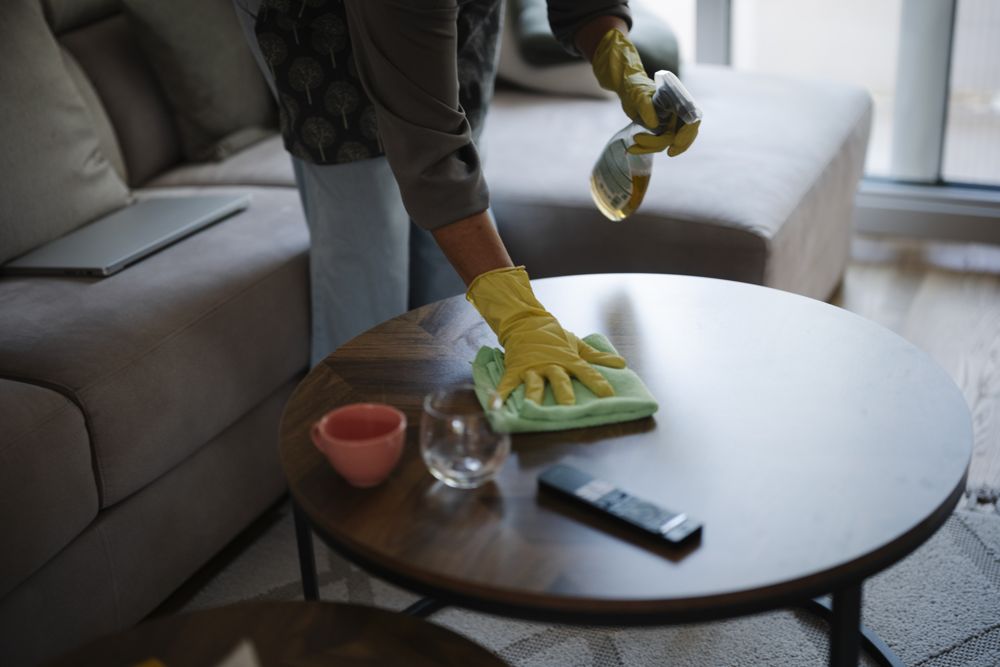 Cleaner wiping a table with gloves and a cloth